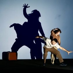 Man and woman dancing in front of a white screen creating beautiful shadows behind them.